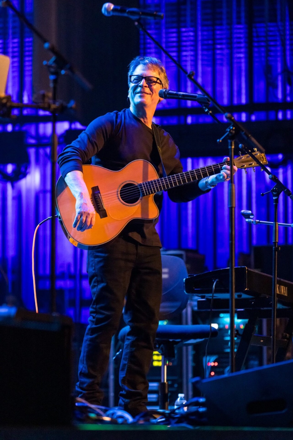 Steve March-Tormé playing acoustic guitar on stage